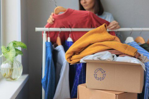 Mujer eligiendo que ropa poner en el contenedor de ropa usada